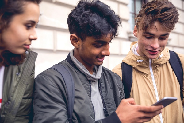 Three people looking at a phone and talking